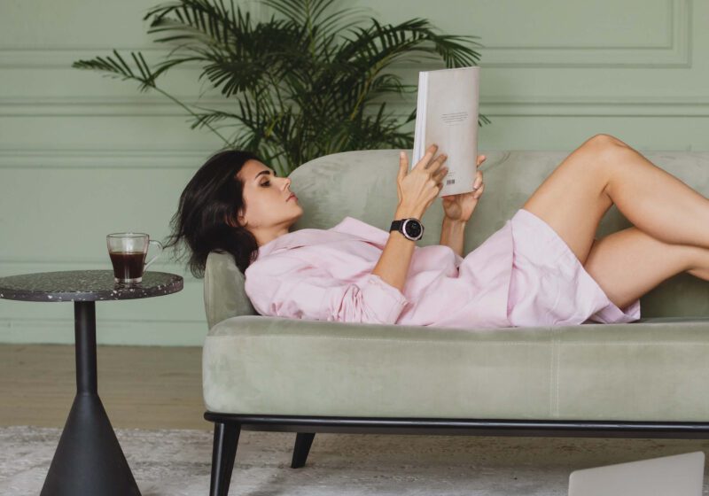 woman reading laying on the couch- 10 daily habits that drastically improved my life