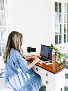 woman wearing a light blue dress working on her laptop: how to keep commitment to yourself