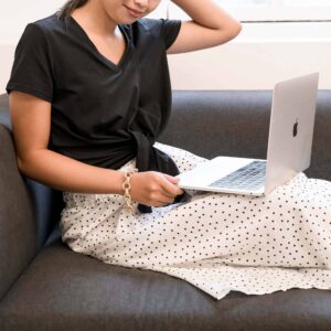 women sitting on a couch and working on her macbook- top 10 priority in life